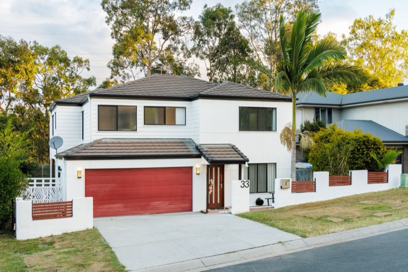 Two-storey residence with timber garage door at dusk
